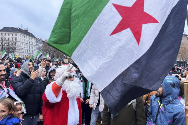 En folkmassa i Berlin – inklusive en tomte – firar den syriska regimens fall.   