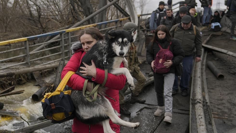 En kvinna håller sin hund i famnen medan de korsar floden i staden Irpin, utanför Kiev i början av mars. FOTO: AP.