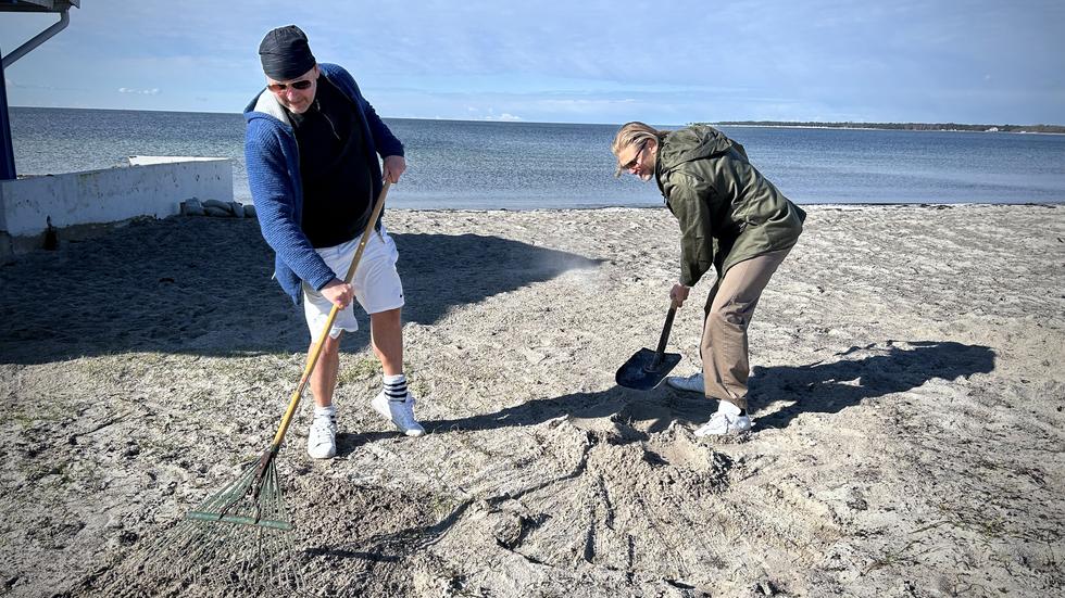 Rikard Björsing och Rikard Tapper, från Kämpinge vattensportklubb, försöker rädda så mycket som möjligt av gräset som ligger begravt under sanden. 