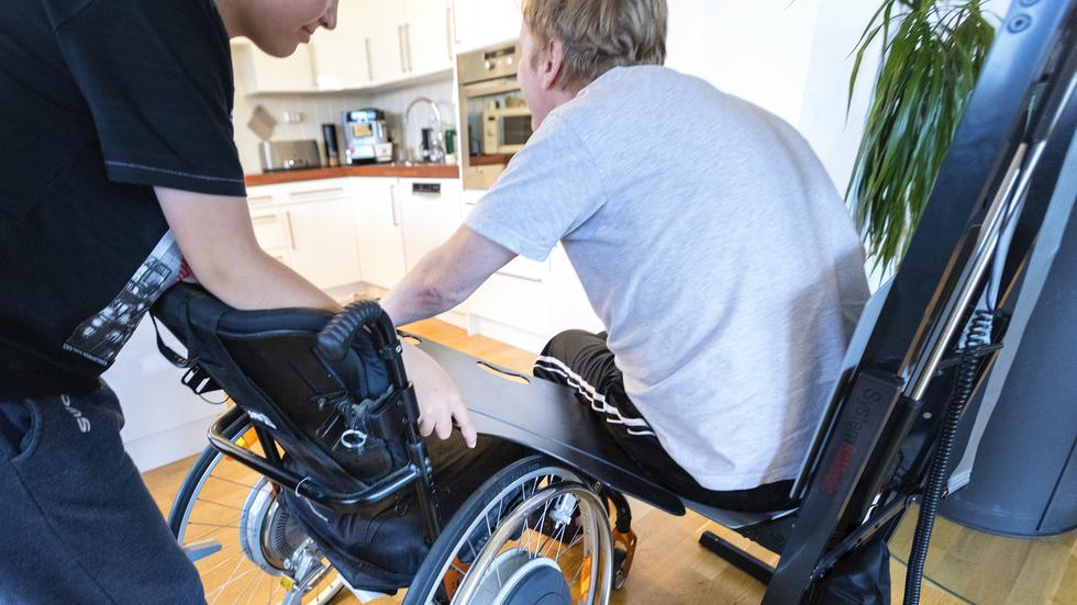 En anhörig hjälper eb funktionshindrad upp i rullstolen efter ett fall.