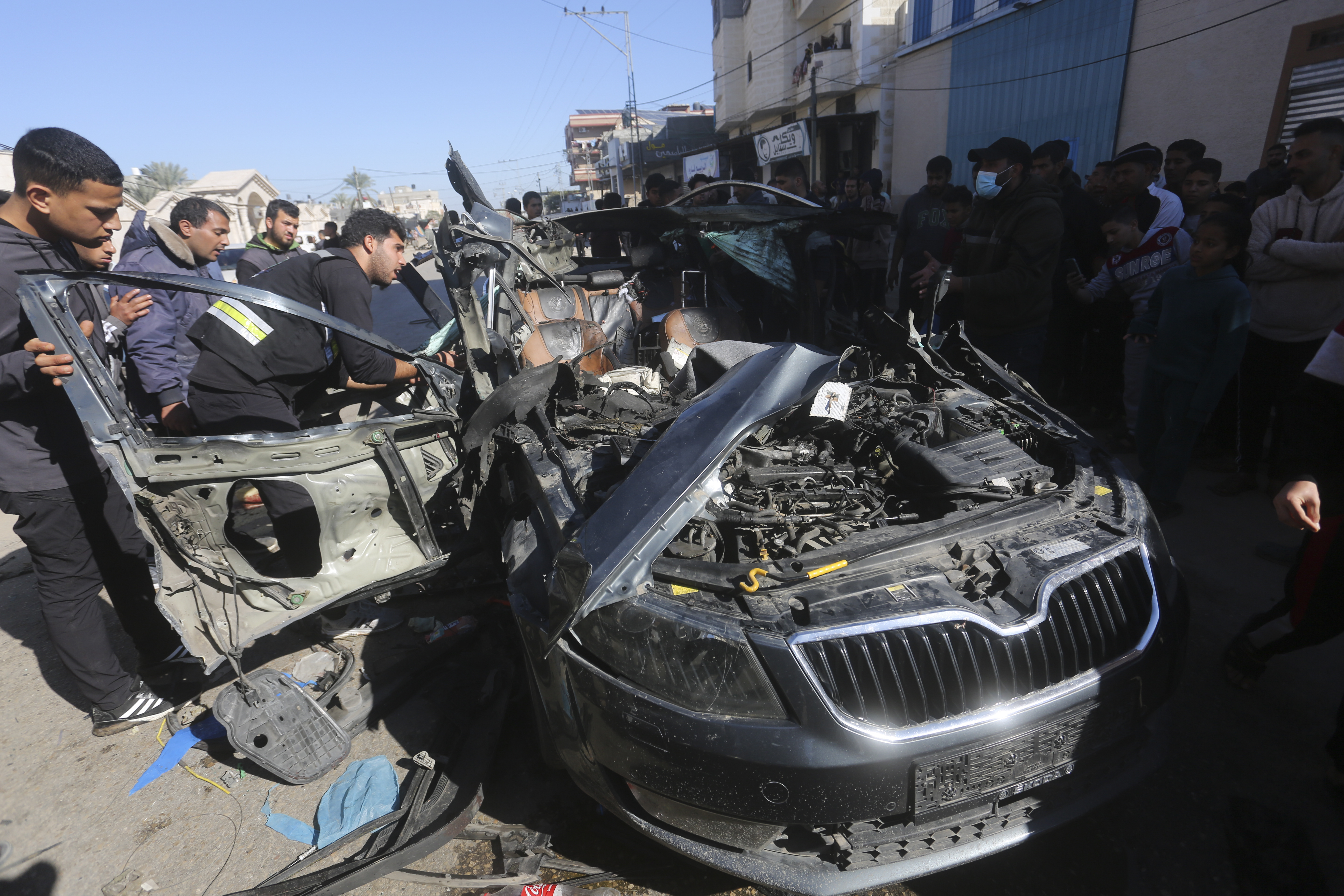 Palestinier tittar på den bil där två journalister dödades i en israelisk flygräd.