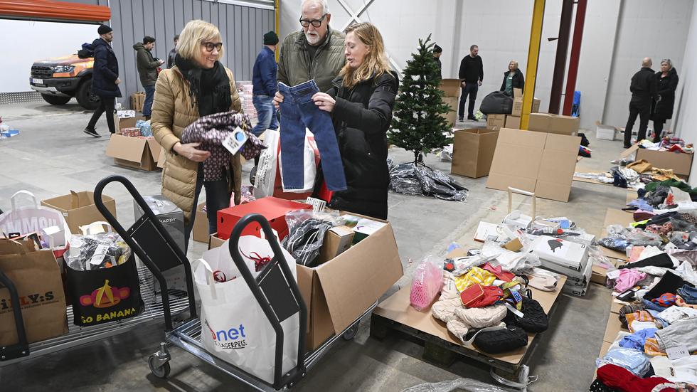 Gunilla och Tommy Söder hjälper Mirijam Hultström att plocka ihop julklappar, här i foem av kläder.