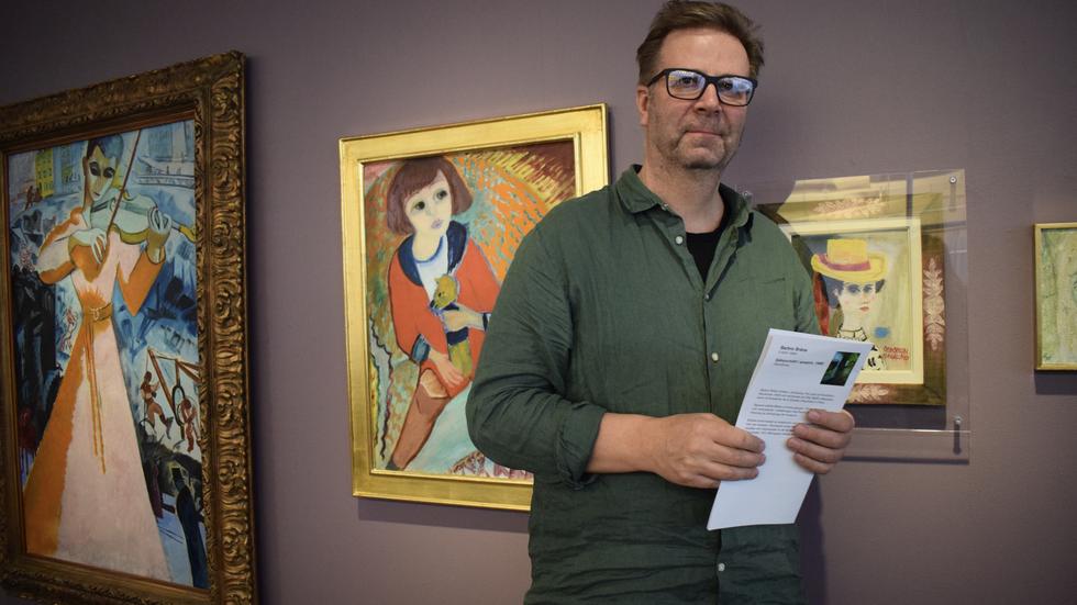 Jonas Nilsson, verksamhetsutvecklare på Länsmuseet. Bakom honom syns två målningar från 1915, skapade av ett känt konstnärspar. Isaac Grünewalds ”Violinisten” och Sigrid Hjerténs ”Ivan med teddybjörn”. 