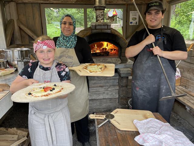Det glada pizzabagarna Edith, Mayyada och Usama trivs i utebakugnen som byggdes under föregående projekt.