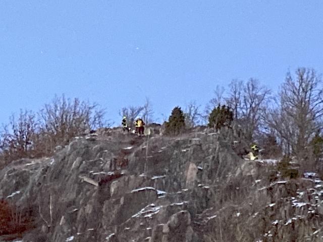 Bänken kan skymtas en bit nedanför brandmännen på berget.