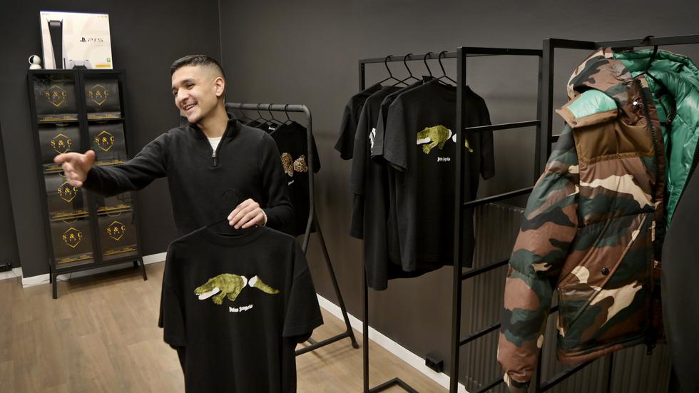 Milad Wazzi visar upp exempel ur sortimentet; en jacka för 15 000 kronor, och en t-shirt för närmare 3 000 kronor.