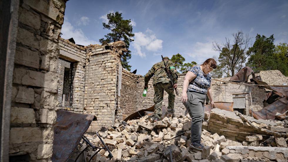 Dmytro Korbut och Valentyna Kunitska går runt och plockar i resterna av sitt hem i byn Gorenka. 