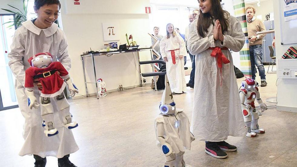 Fyra robotar lussar tillsammans med fyra femteklassare från Videdalsskolan i Malmö.