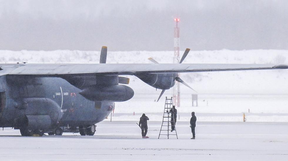 Personer undersöker det franska militära Hercules-plan som fick motorproblem på en flygning från Kiruna.