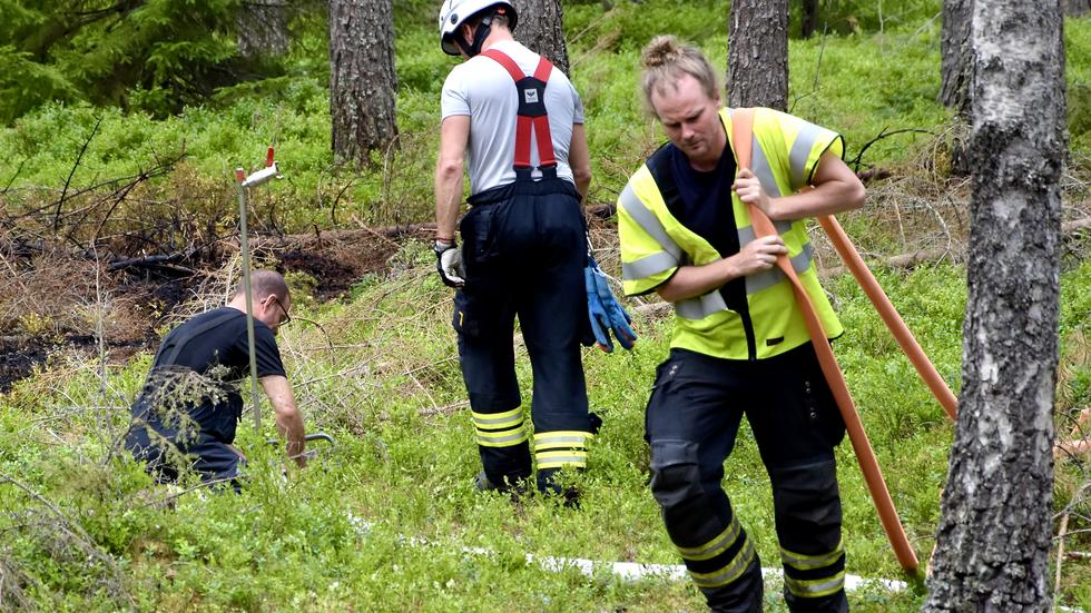 Brandmän arbetar under en av bränderna, vid Villagatan/Gamla landsvägen i Mullsjö, 5 juli 2021. Kvinnan är inte misstänkt för branden.