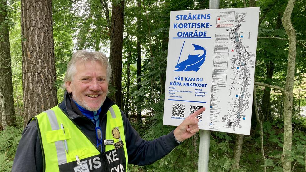Michael Bergström, vice ordförande i Stråkens Fiskevårdsområdesförening (Fvof), visar den nya informationsspäckade skylten som har satts upp vid Stråken. 