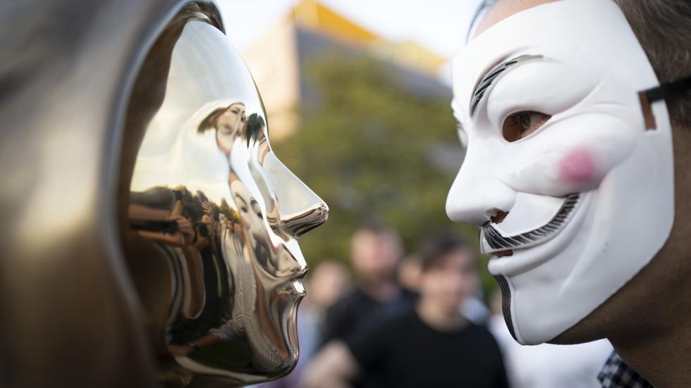 En staty som ska symbolisera bitcoins grundare Satoshi Nakamoto till vänster och en person i Guy Fawkes-mask till höger. Arkivbild från ett evenemang i Budapest.