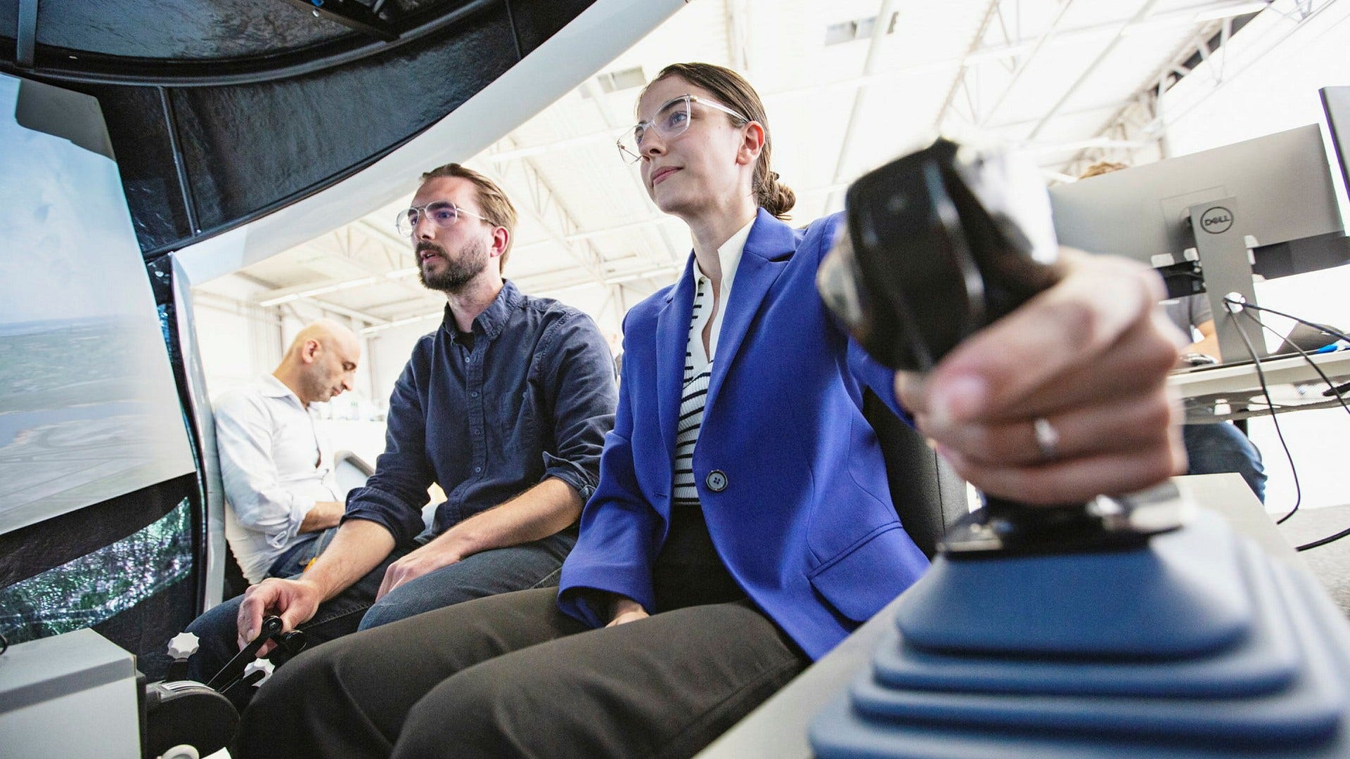 Romina Pourmokhtari testar flygsimulatorn hos Heart Aerospace under testpiloten Oskar Dahls överinseende.