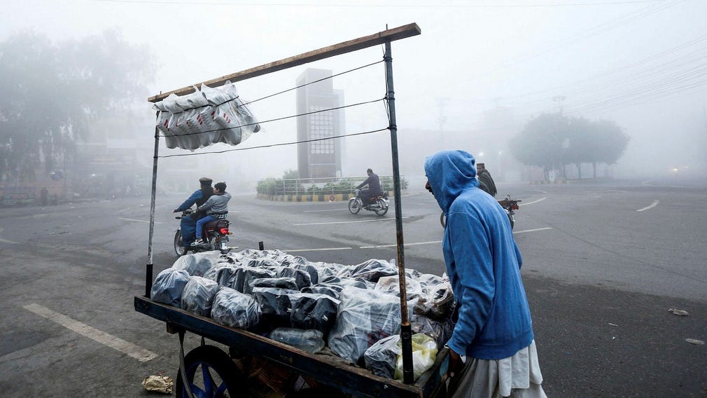 En skoförsäljare skjuter sin vagn längs en gata uppslukad av smog, i Multan den 17 november 2024. Pakistans folkrikaste Punjab-provins förlängde den 15 november skolnedläggningar i smogdrabbade storstäder med en vecka, med tusentals inlagda på sjukhus eftersom landets strider rekord luftförorening.