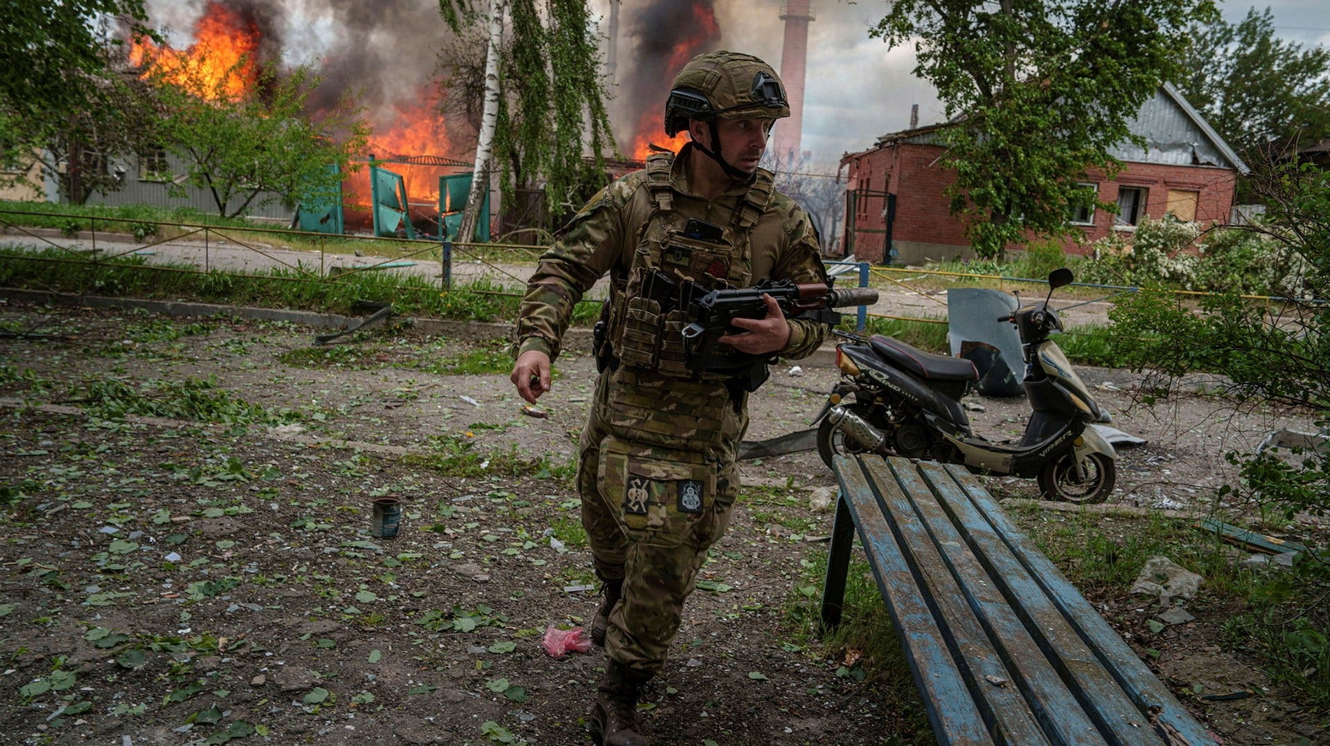 En soldat framför ett brinnande hus som träffas under ett ryskt luftanfall i den ukrainska staden Vovtjansk norr om Charkiv.