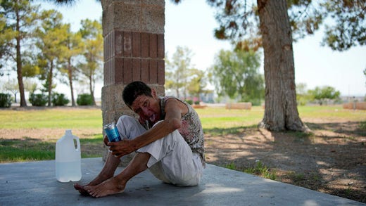 Deb Bellett, 66, drinks water in Henderson, Nevada, U.S., on July 10. She waits for an ambulance to take her to the hospital with heat-related symptoms.