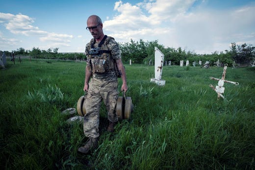 En ukrainsk soldat bär bort ryska minor från en gravplats i Donetsk-regionen. Bilden är från maj i år.