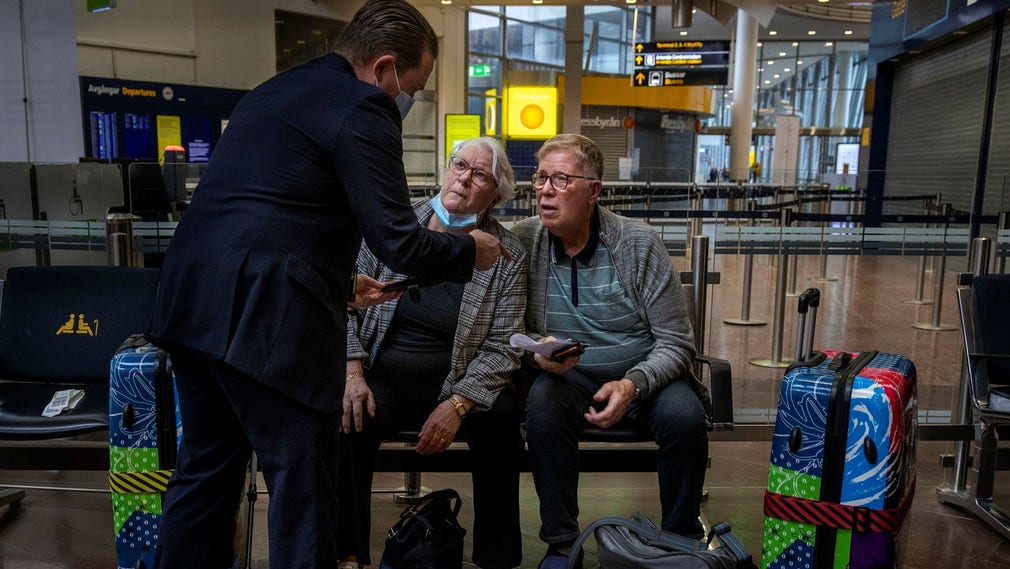 En flygplatsanställd hjälper Lillemor Ståhlbom och Bjarne Angeltoft att försöka komma åt svaret från ett pcr-test, som behövs för att komma in i Spanien.