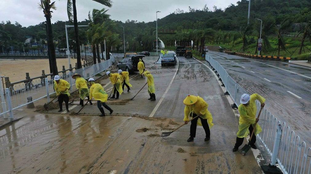 Arbetare i staden Zhuhai städar gatorna efter att tyfonen Saola dragit in över Kina.