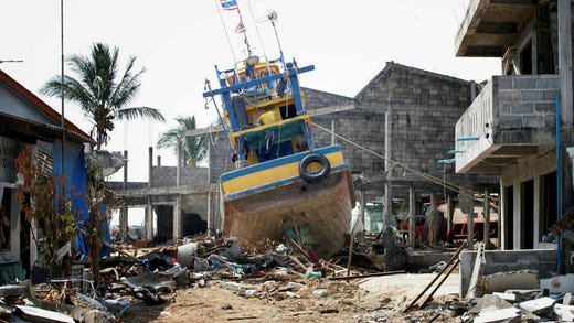 En fiskebåt spolas upp bland husen i den lilla fiskebyn Nam Kem i Thailand den 7 januari 2005.