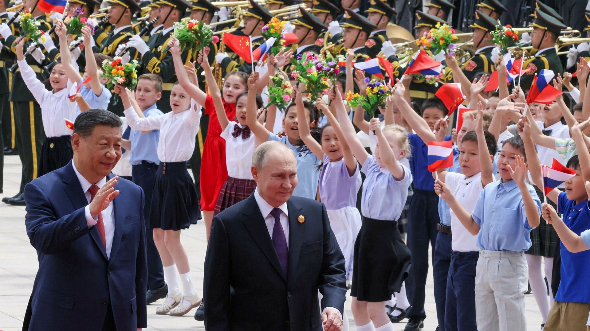 Bambini russi e cinesi esultano in piazza Tiananmen a Pechino mentre passano il leader cinese Xi Jinping e il presidente russo Vladimir Putin.  Putin è in visita di due giorni in Cina.