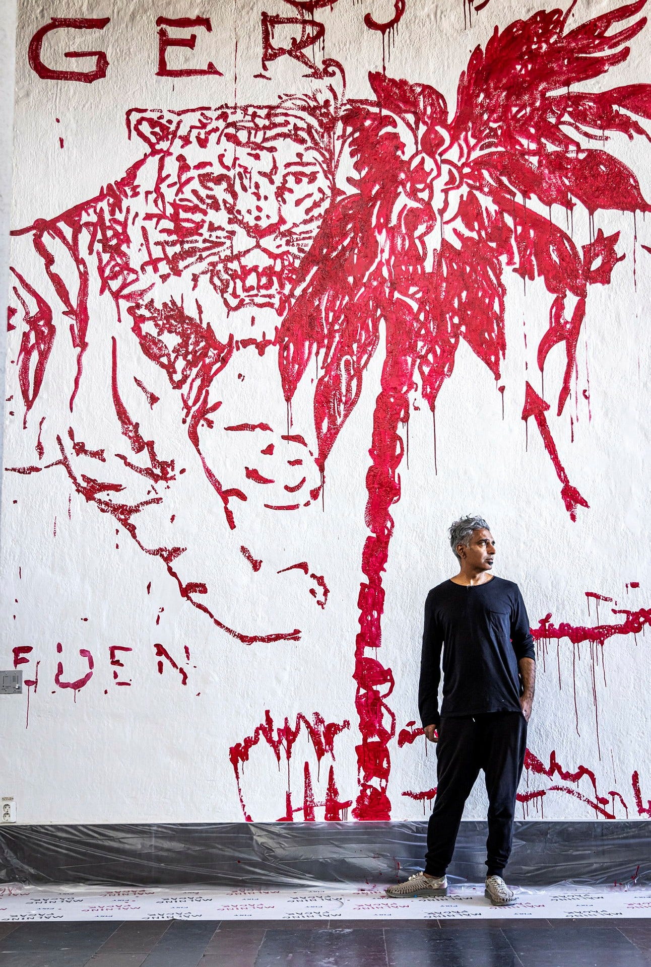 Manish è visibile davanti al suo murale rosso con tigri e palme.