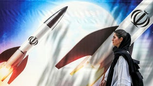 En kvinna i Irans huvudstad Teheran passerar framför en propagandaaffisch.