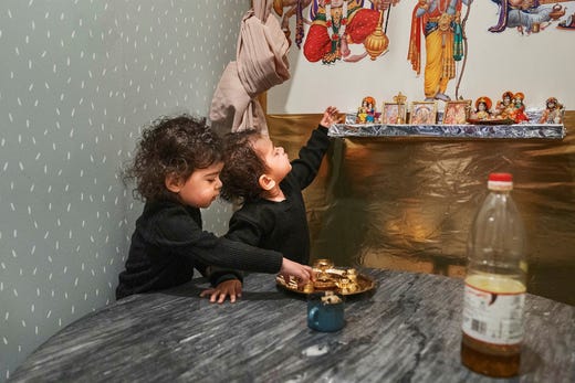 Tvillingarna Kisha och Kiaan, 2 år, är i klädaffären som är den hinduiska familjens tempel där de ber morgon och kväll.