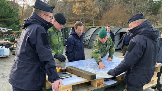 Marinens befälhavare ger orientering inför demonstrationen. Här pekar överste Fredrik Herlitz, chef för Amf 4, på kartan medan ÖB Michael Claesson och statsminister Ulf Kristersson lyssnar.