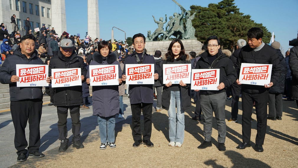 En grupp demonstranter poserar med sitt budskap: President Yoon, avgå!