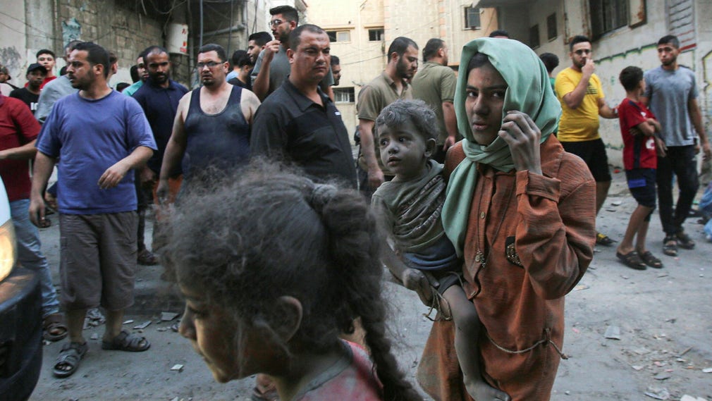 Gaza den 12 oktober. En kvinna och ett barn är täckta av damm och smuts efter en israelisk attack.