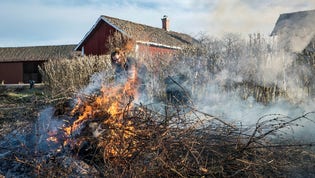 En kvinna eldar trädgårdsavfall tidig vår i Södermanland.