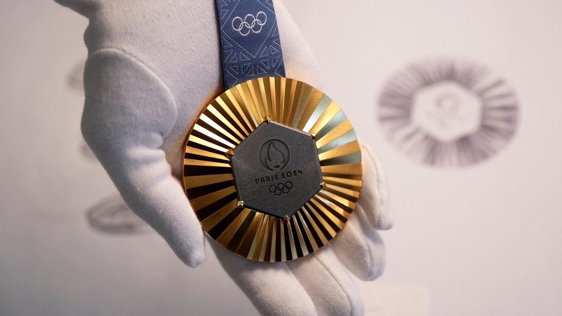 Så ser en guldmedalj i OS 2024 ut. Den sexkantiga mörka delen av medaljen består av järn från Eiffeltornet.