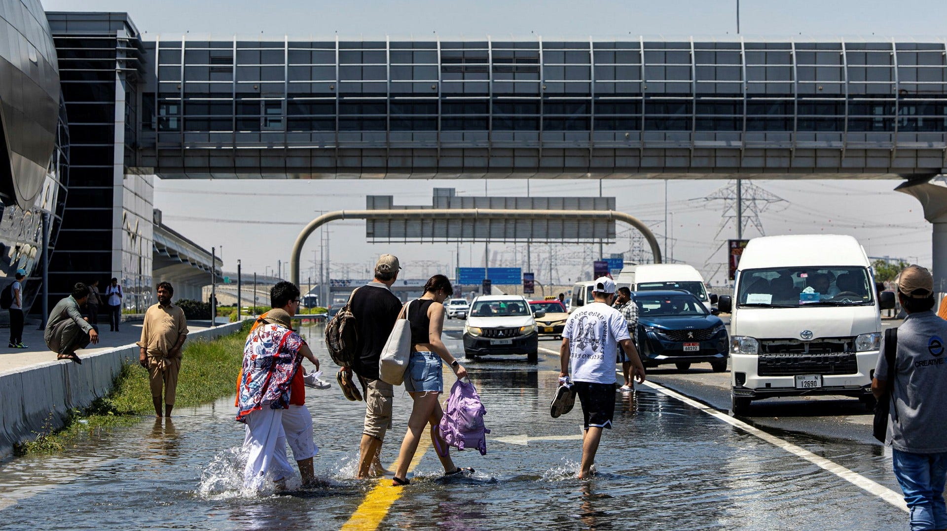 People walking across a flooded road in Dubai.