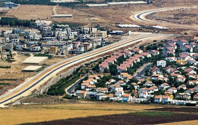 En palestinsk by (till vänster) separeras från en israelisk bosättning på Västbanken av den skyddsmur Israel har byggt på ockuperat område. Nya beslut om bosättningar den senaste tiden har försvårat processen mot en tvåstatslösning, skriver Margot Wallström.