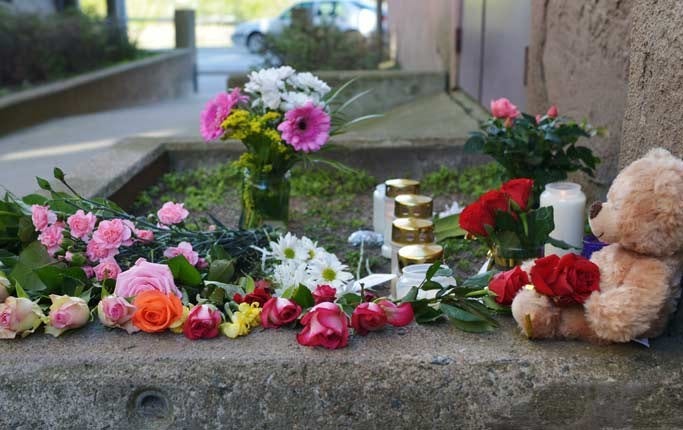 Blommor, ljus och en nalle lyser upp utanför porten till det hus i centrala Karlskrona där den åttaåriga flickan bodde.