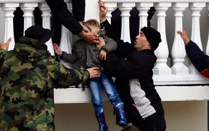 Serbiska soldater evakuerar en pojke från familjens översvämmade hus i staden Obrenovac.