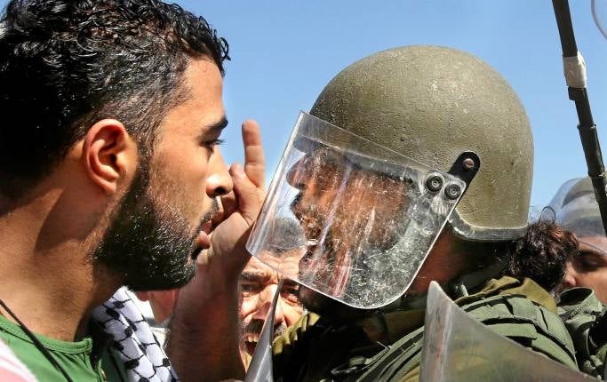 Palestinsk demonstrant och israelisk soldat vid vägspärren Hawara, nära Nablus på Västbanken. Bilden togs i måndags, i samband med protester mot bombningarna av Gaza.