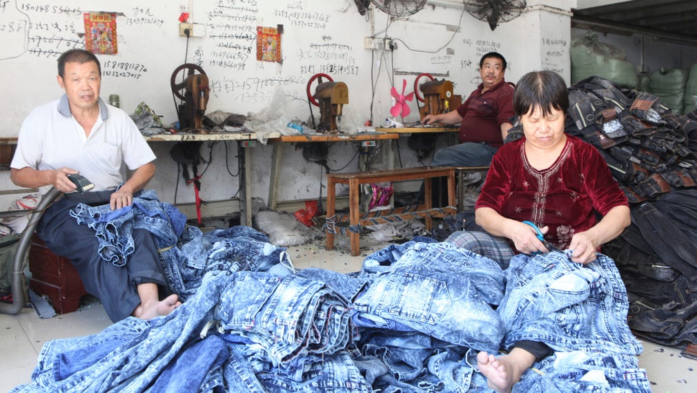 Li Zhiqiang och fru Chen, båda från Sichuanprovinsen, finputsar på jeans som snart ska fraktas till Afrika.
