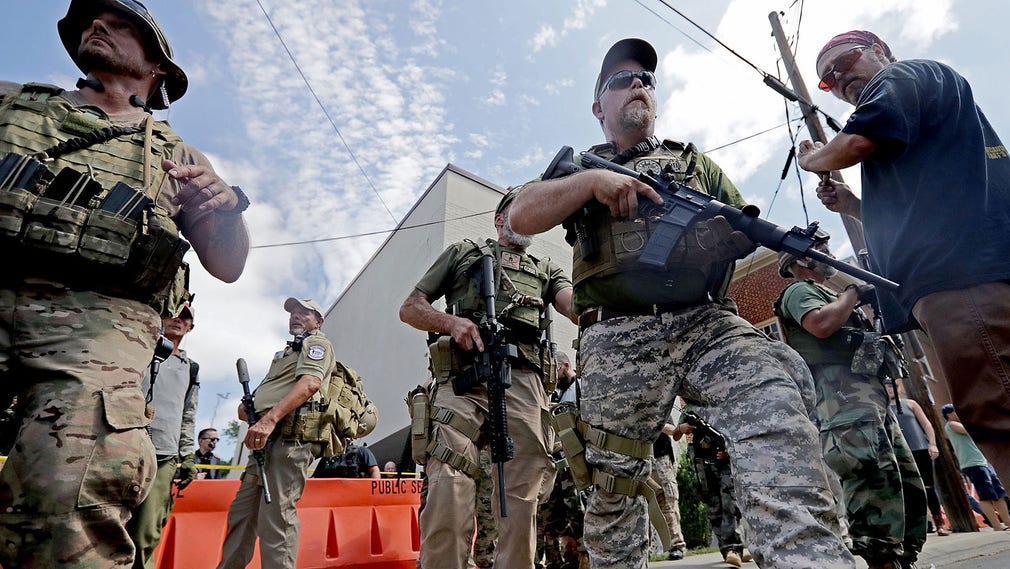 Beväpnade Vit makt-aktivister försöker evakuera sympatisörer som utsatts för pepparsprej. Demonstrationen ”Förena högern” har förklarats olaglig av delstaten Virginia.