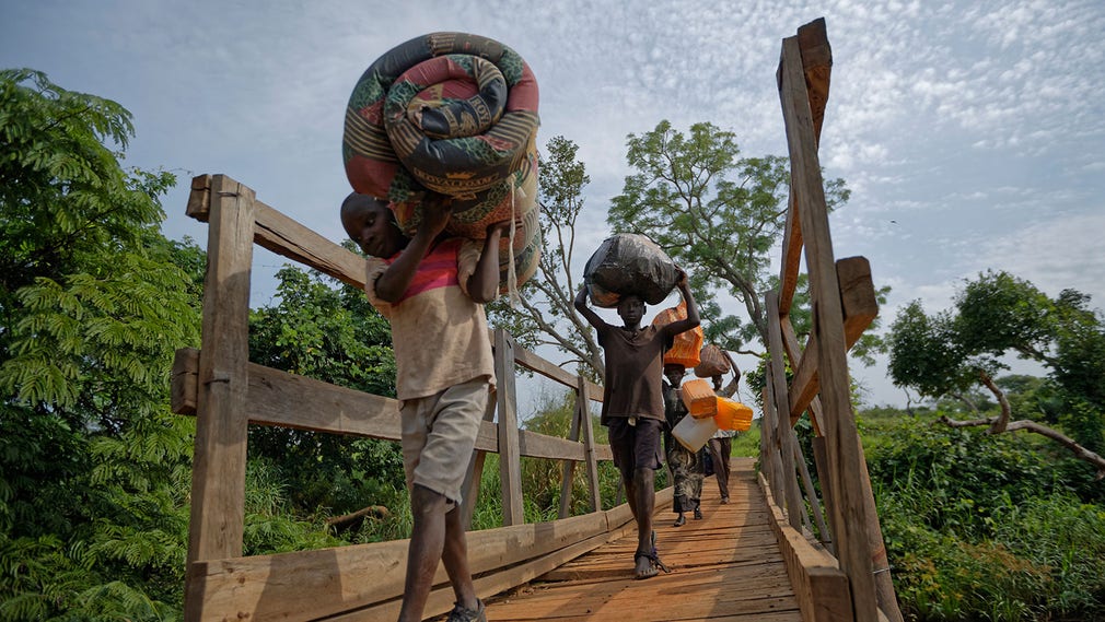 Sydsudanesiska flyktingar på väg över en bro till Uganda. Thomas Wani, Peter Lemi, Rose Sunday, och deras pappa Julius Lezu.