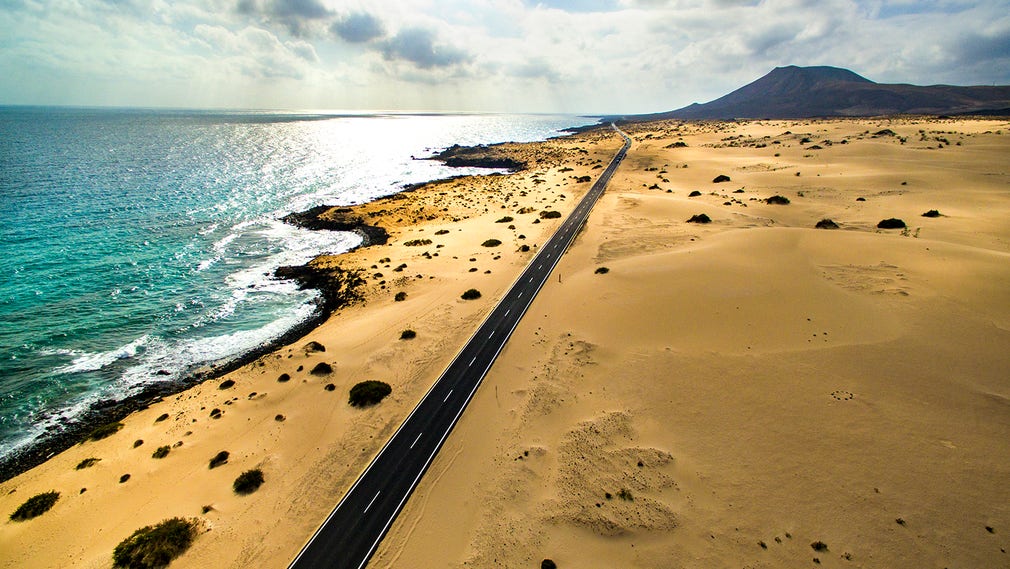Väg FV-1 skär genom Parque Natural de las Dunas de Corralejo med dess sanddyner som sträcker sig nästan ända ner till havet.
