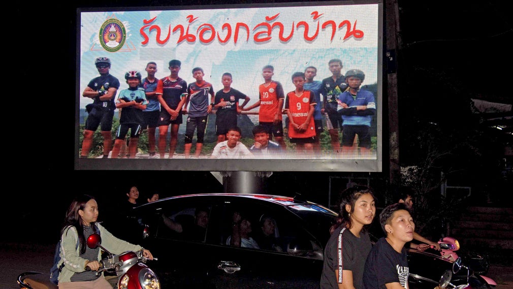 ”Välkommen hem, bröder”, står det på en reklamtavla föreställande de tolv pojkarna och deras fotbollstränare som blev fast i grottan i Tham Luang men som nu har räddats.
