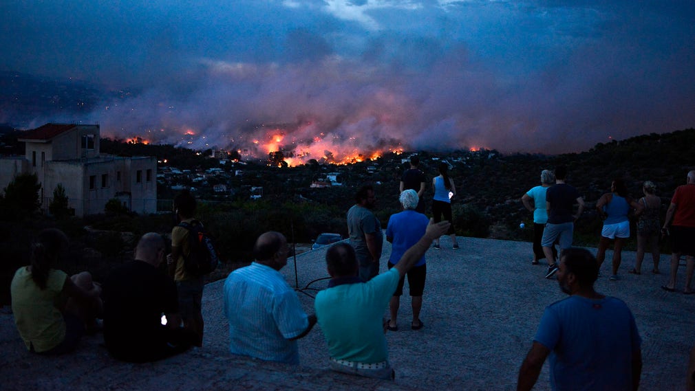 Invånare i staden Rafina, öster om Aten, betraktar branden på avstånd.
