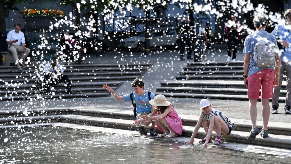 Några barn svalkar sig i fontänen i Kungsträdgården.