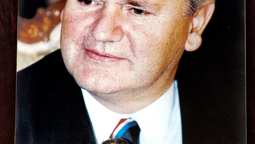 Peter Handke håller ett tal 2006 med ett stort porträtt av Slobodan Milosevic bakom ryggen. Talet hölls strax före Milosevics begravning.