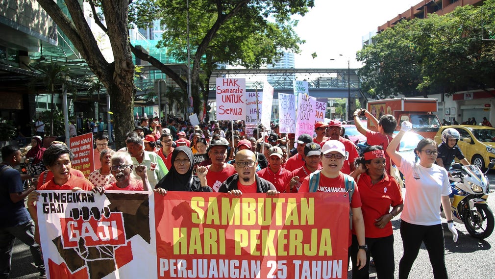 ”Höjning av lön och stoppa diskriminering” på banderoll i Kuala Lumpur.