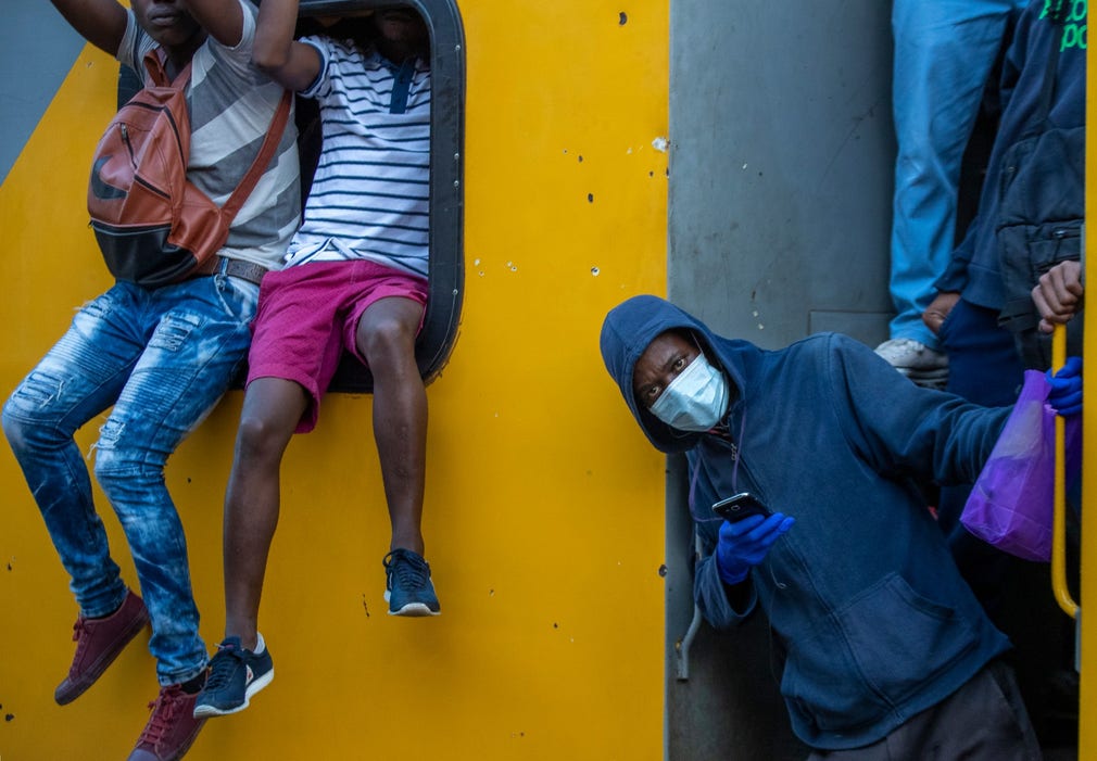 Pendlare håller sig fast på utsidan av en tåg i Soweto utanför Johannesburg i Sydafrika.