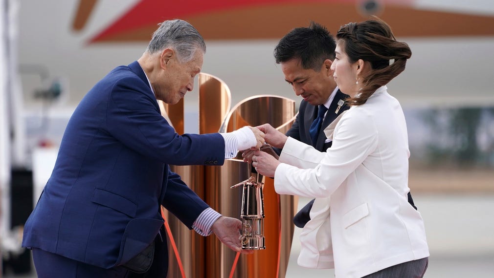 Tokyo 2020-chefen Yoshiro Mori tar emot den olympiska elden av de japanska OS-guldmedaljörerna Tadahiro Nomura och Saori Yoshida.