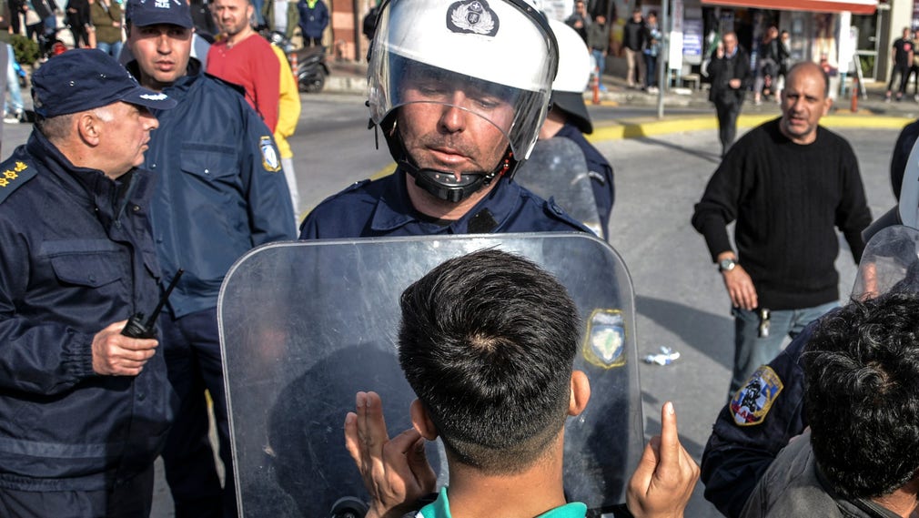 En flykting och en grekisk polisman i hamnen i Mytilene på ön Lesbos i tisdags.
